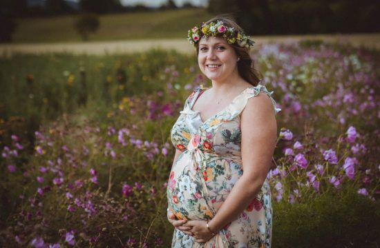 Schwangere steht in Blumenfeld