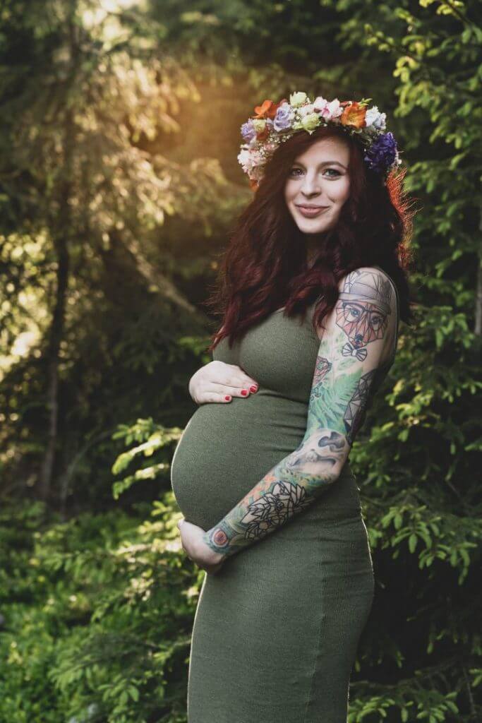 Schwangere mit Tattoos hält Babybauch