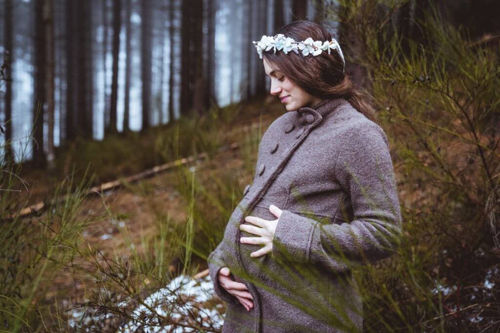 Schwangere hält Babybauch im Wald