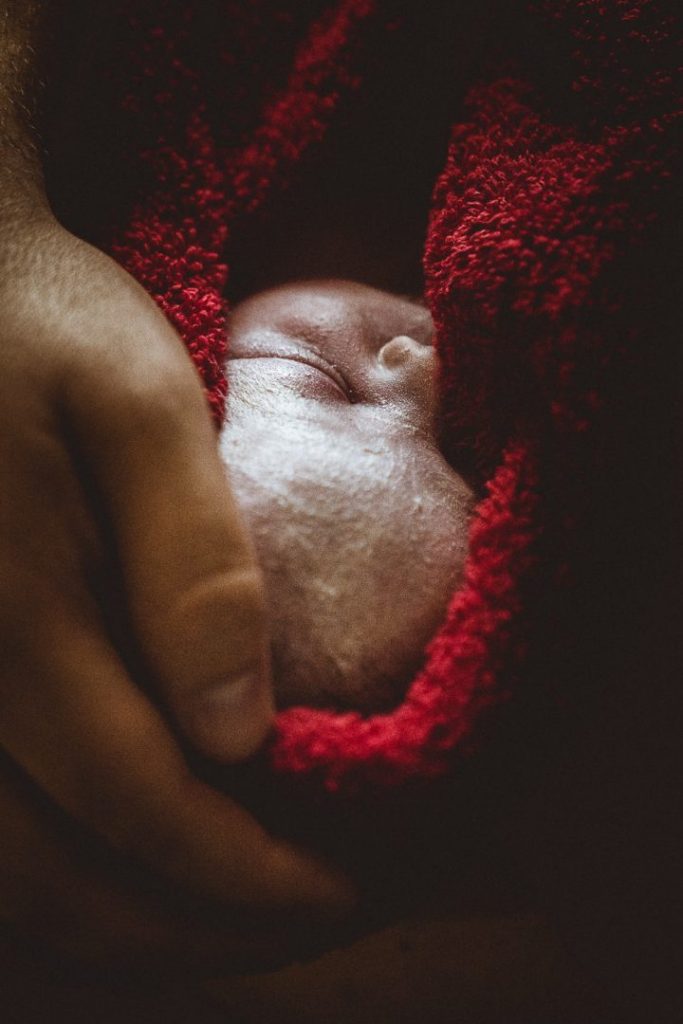 Nahaufnahme neugeborenes Babygesicht in rotem Handtuch