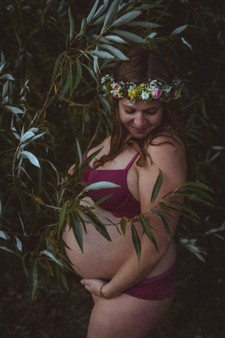 Schwangere steht in Unterwäsche in Busch