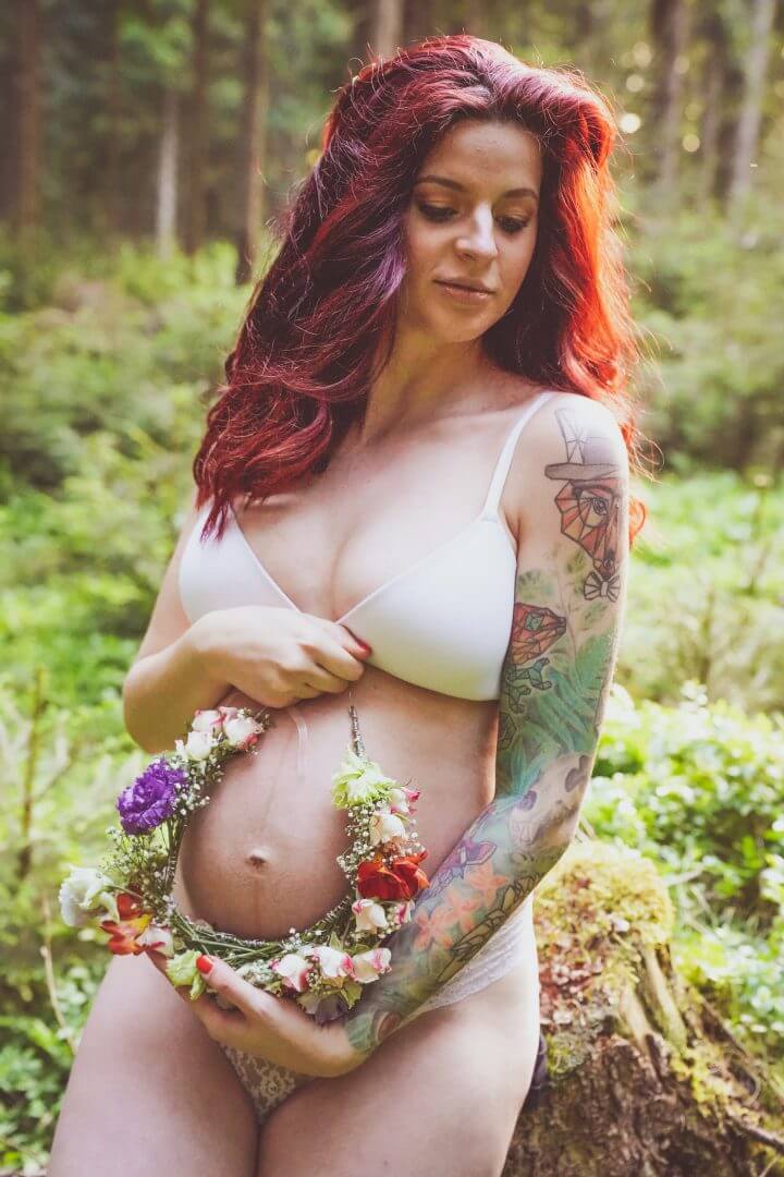 Schwangere steht in Unterwäsche in Wald