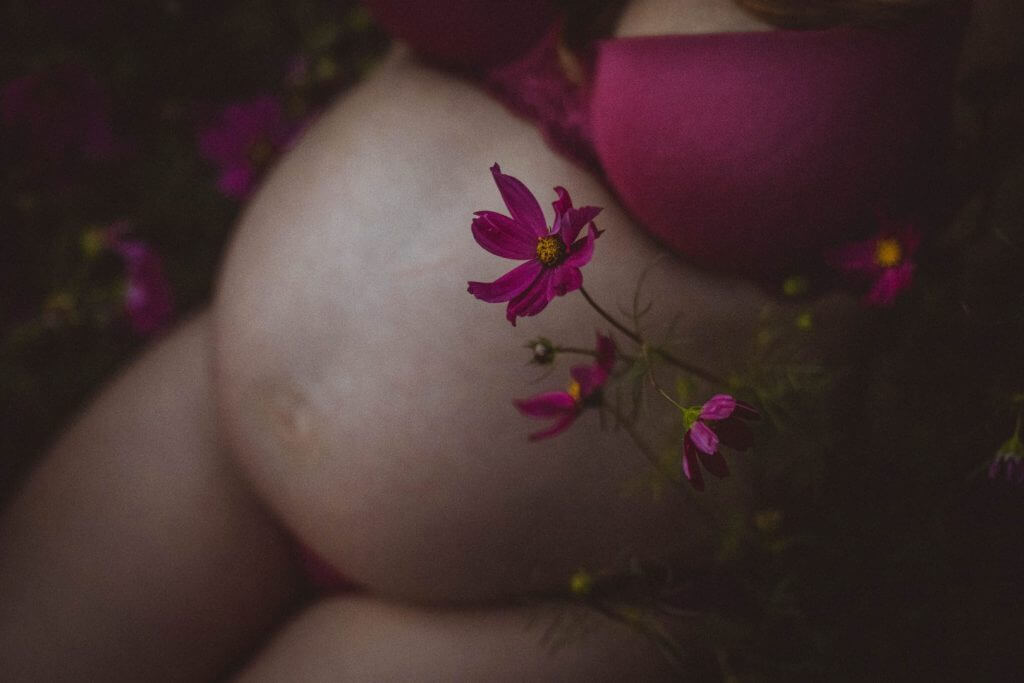 Nahaufnahme Babybauch mit pinken Blüten