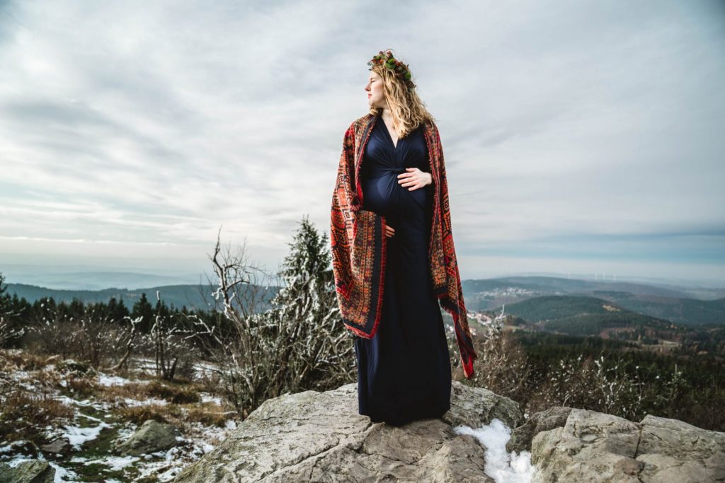Schwangere in blauem Kleid auf Fels