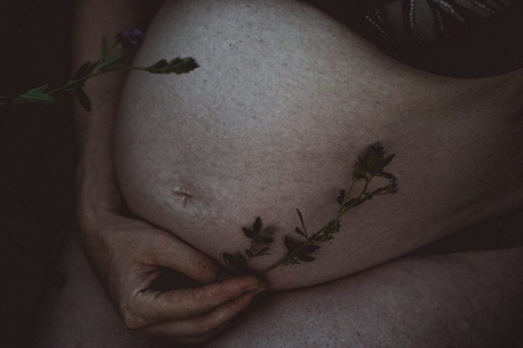 Nahaufnahme Babybauch mit Blüte