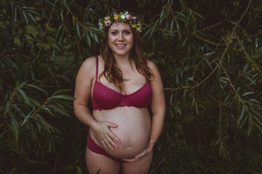 Schwangere in pinker Unterwäsche steht unter Weide