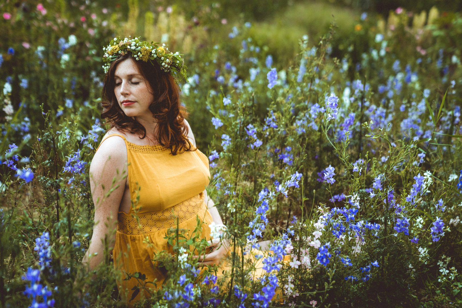 Schwangere in blauem Blütenfeld