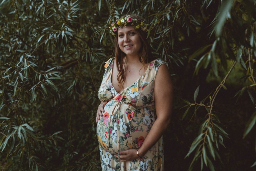 Schwangere in Blumenkleid unter Weide