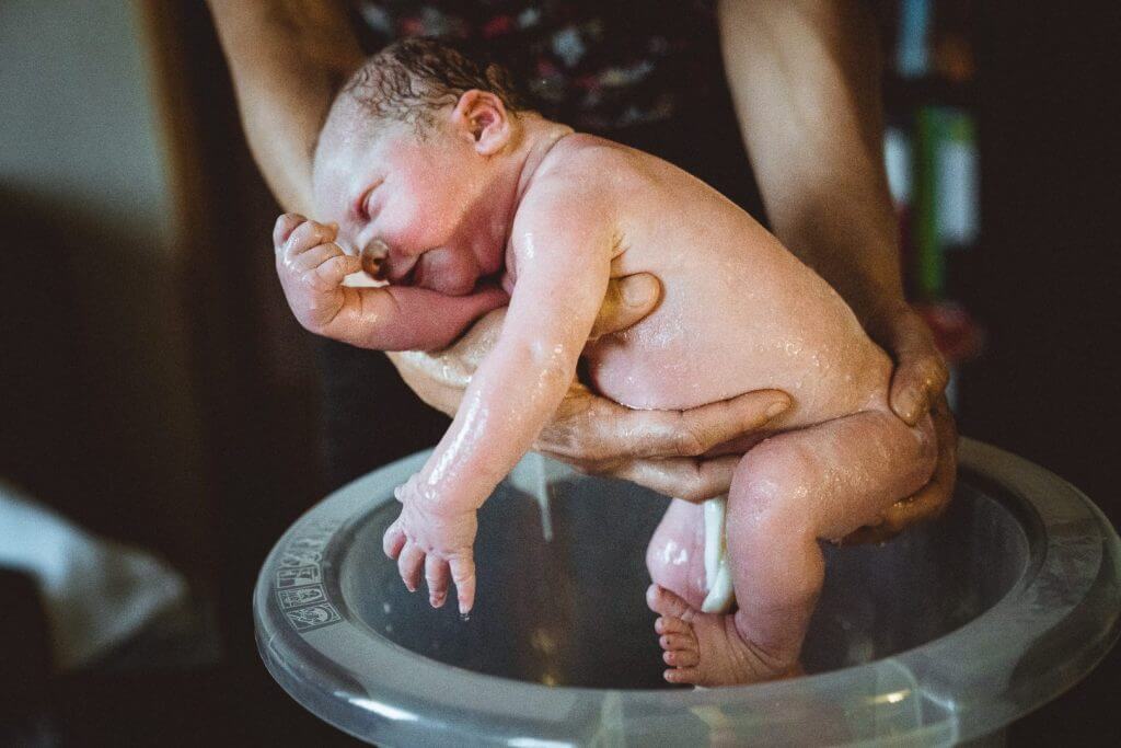Neugeborenes wird gebadet nach Geburt
