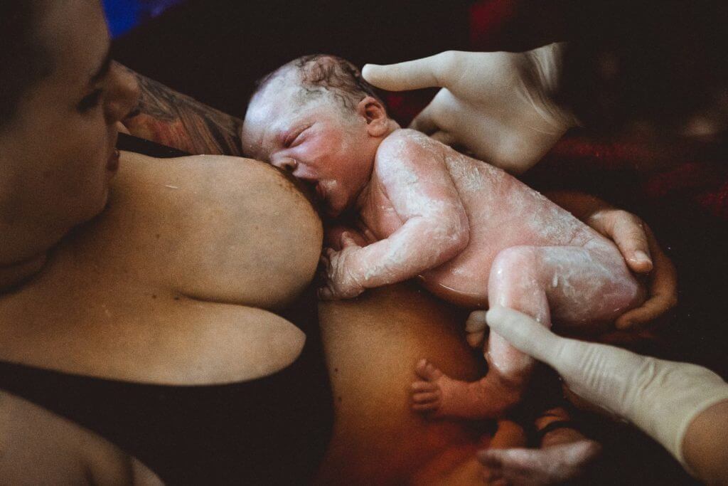 Baby stillt nach Hausgeburt im Geburtspool