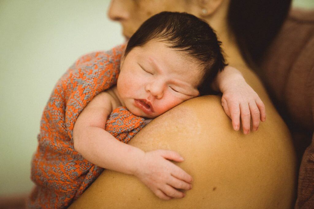 Neugeborenes schläft auf Mutters Schulter