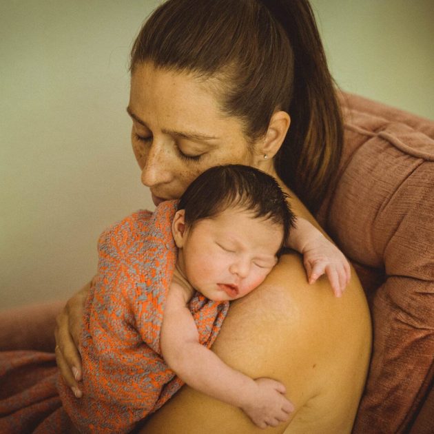 Neugeborenes in rosa Decke auf Arm der Mutter