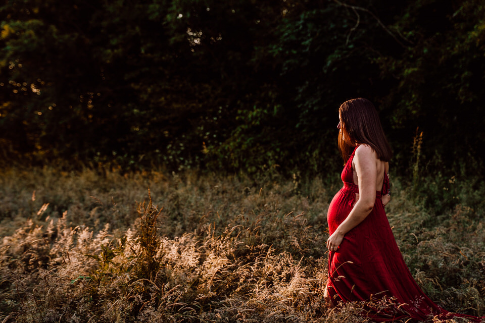 Schwangere in rotem Kleid vor Wald