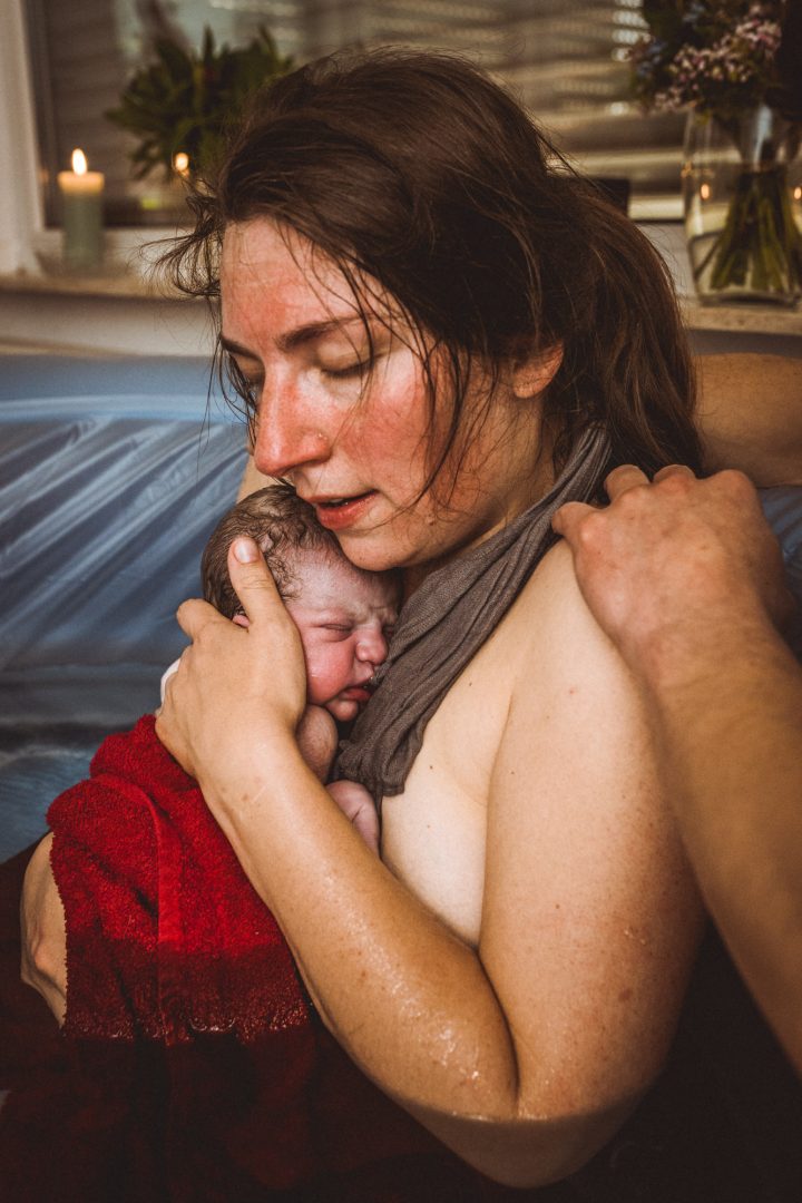 Mama kuschelt Baby nach Geburt im Pool