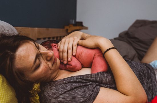 Mama kuschelt Baby auf ihrer Brust nach Hausgeburt
