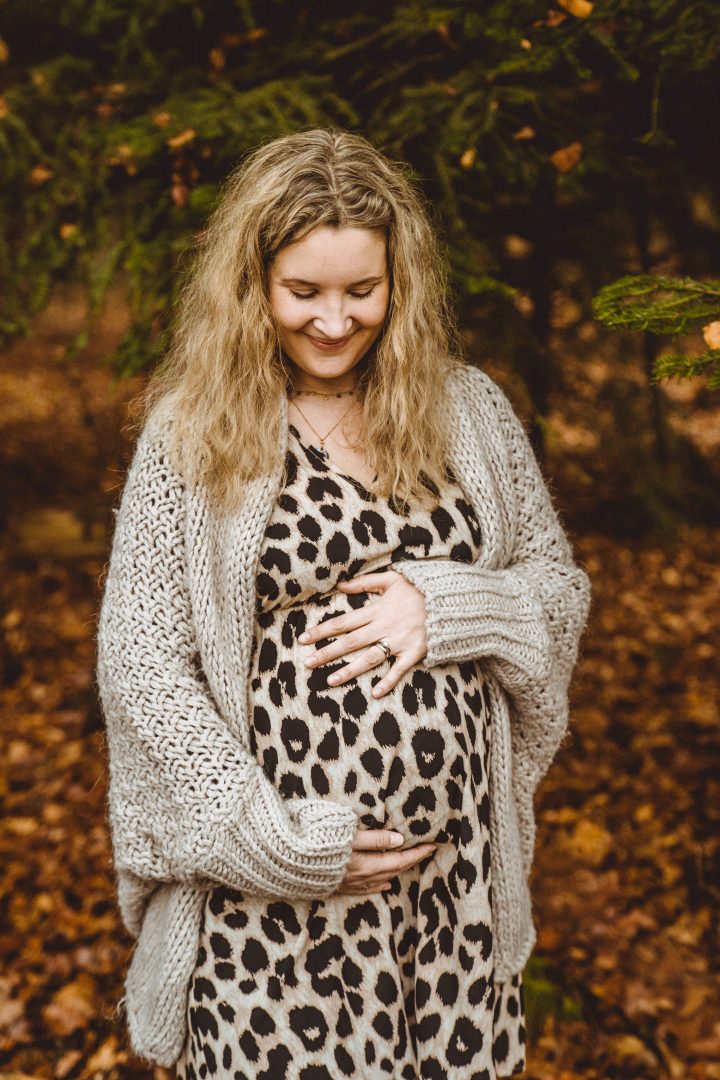 Schwangere hält Babybauch vor Wald