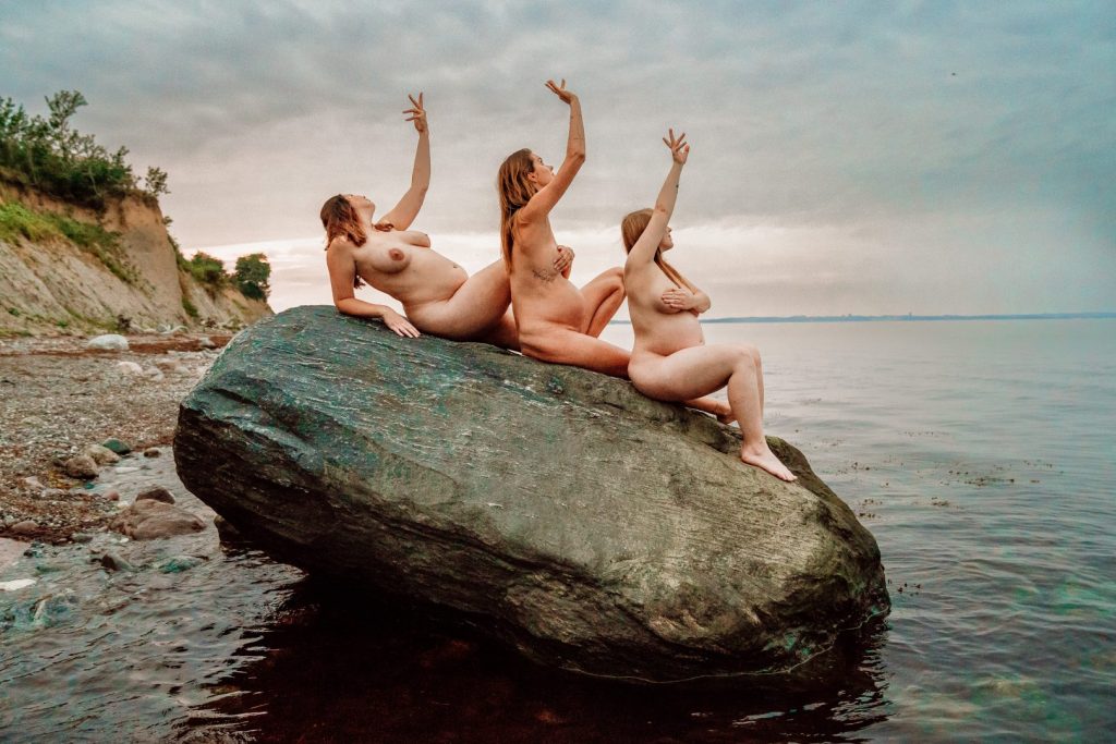 Drei Schwangere auf Fels im Meer
