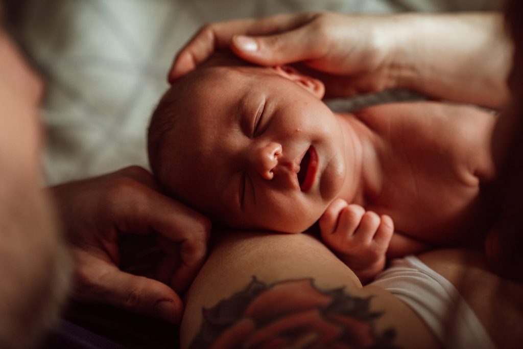 Baby wird von Eltern im Gesicht gestreichelt