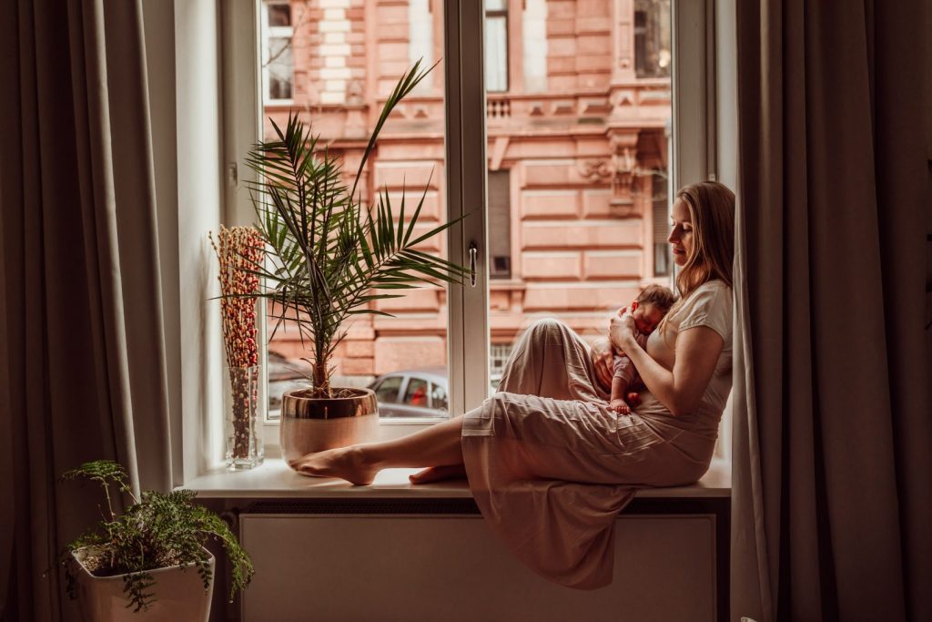 Mutter stillt Baby auf Fensterbank