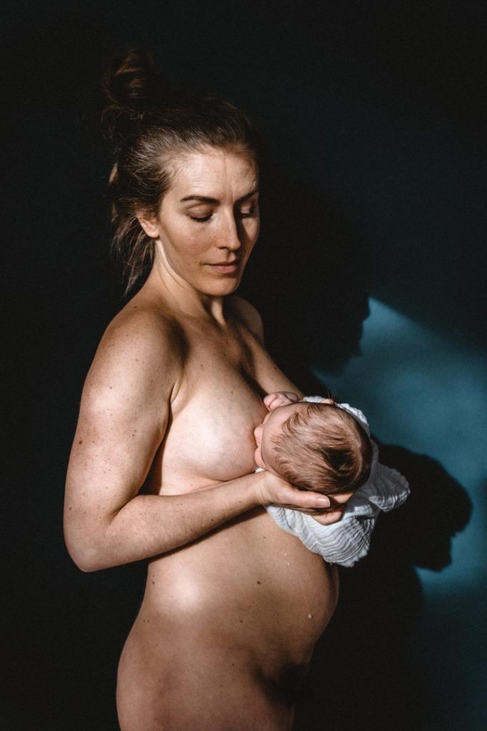 Mutter stillt Baby vor blauer Wand