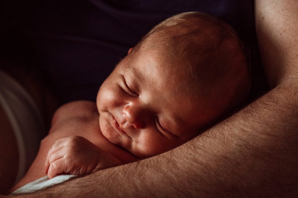 Baby schläft in Papas Armen