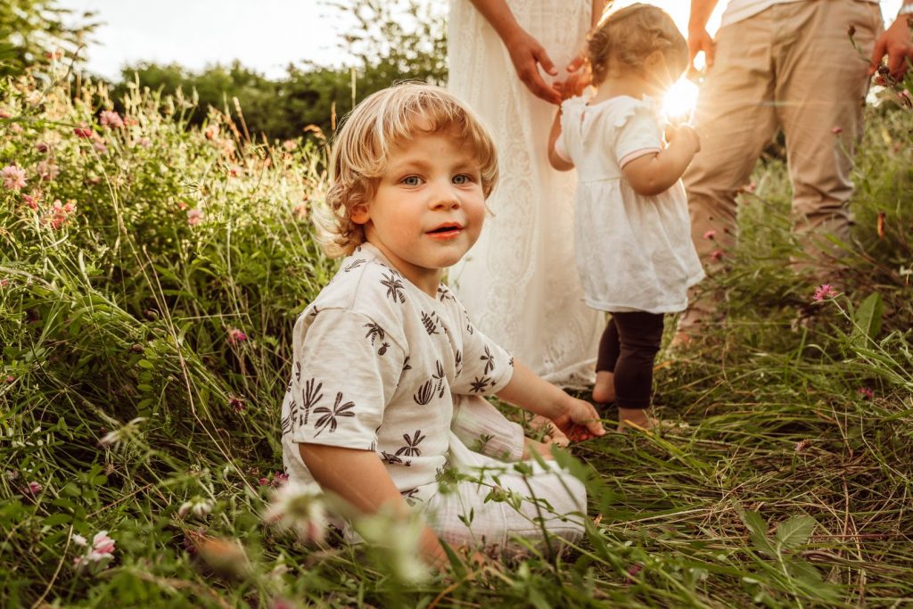 Blonder Junge sitzt in Gras