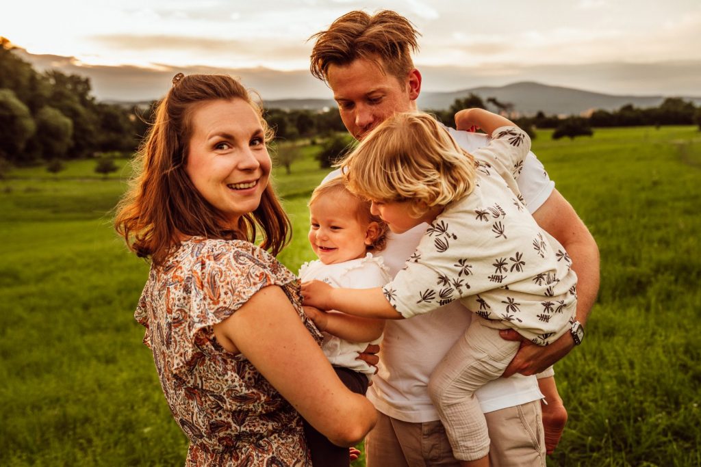 Familie hält sich im Arm und blickt in Kamera