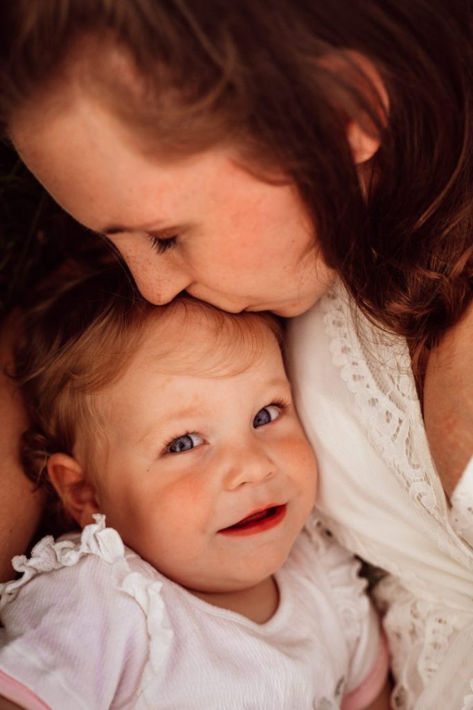Mama küsst Kleinkind auf Stirn